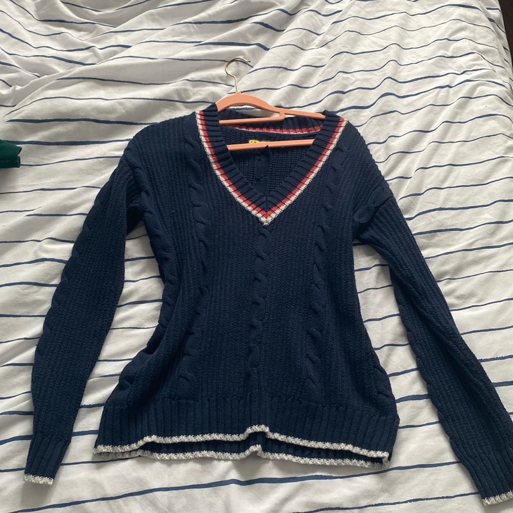 navy blue v neck sweater with red and white lining at vneck. It is also knitted
